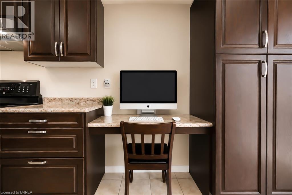 Integrated workspace featuring a built-in desk with a light-toned countertop, flanked by dark wood-finish cabinetry - 26 Pollard Street, Brantford, ON - Indoor Photo Showing Kitchen