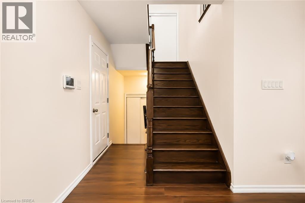 Rich wood-finish flooring and a matching staircase with dark wood newel posts - 26 Pollard Street, Brantford, ON - Indoor Photo Showing Other Room