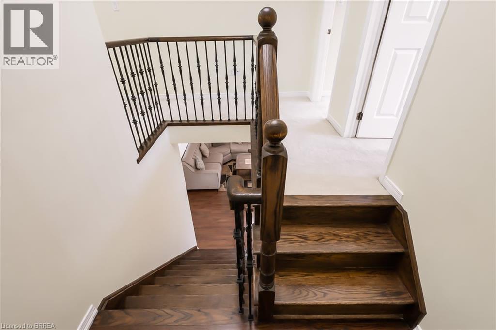 Hardwood staircase with dark wood-finish treads and risers, complemented by a wrought iron and wood balustrade - 26 Pollard Street, Brantford, ON - Indoor Photo Showing Other Room