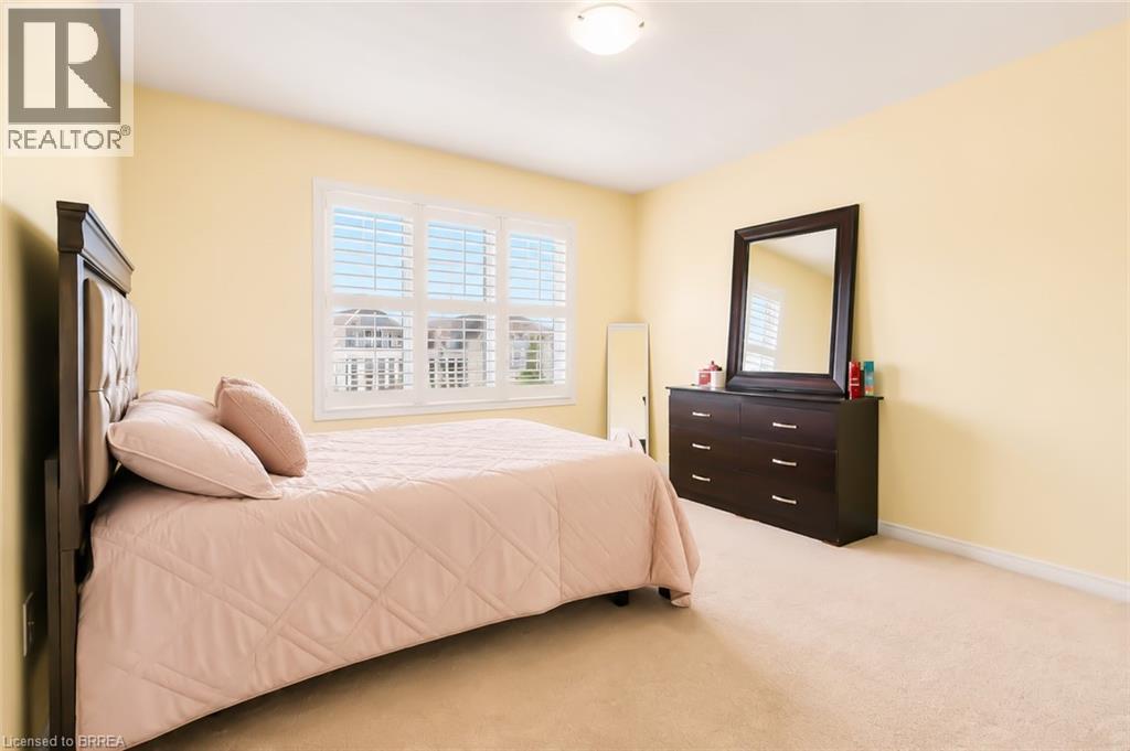 Carpeted room with a multi-pane window featuring white plantation shutters - 26 Pollard Street, Brantford, ON - Indoor Photo Showing Bedroom