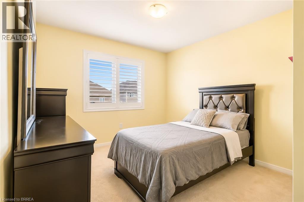 Carpeted room featuring a white window with louvered shutters, a built-in ceiling light fixture, and pale yellow walls - 26 Pollard Street, Brantford, ON - Indoor Photo Showing Bedroom
