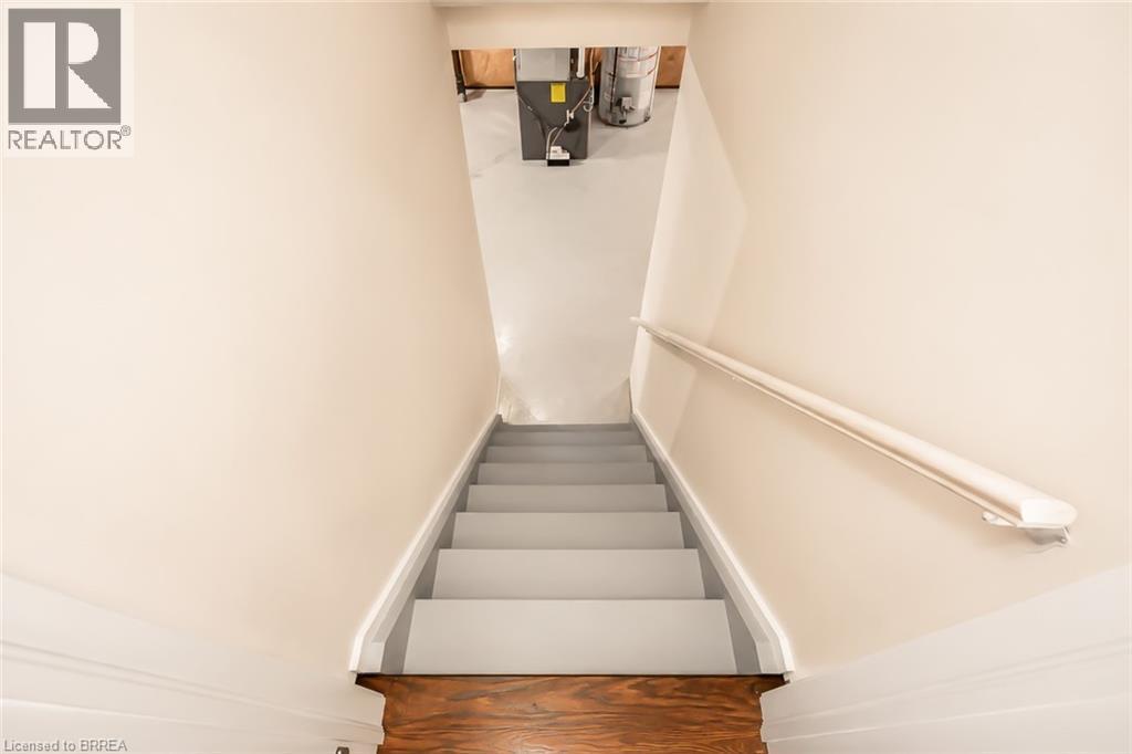 Stairwell with painted treads and risers, white handrail, light-toned wall paint, and wood-finish flooring at the base - 26 Pollard Street, Brantford, ON - Indoor Photo Showing Other Room