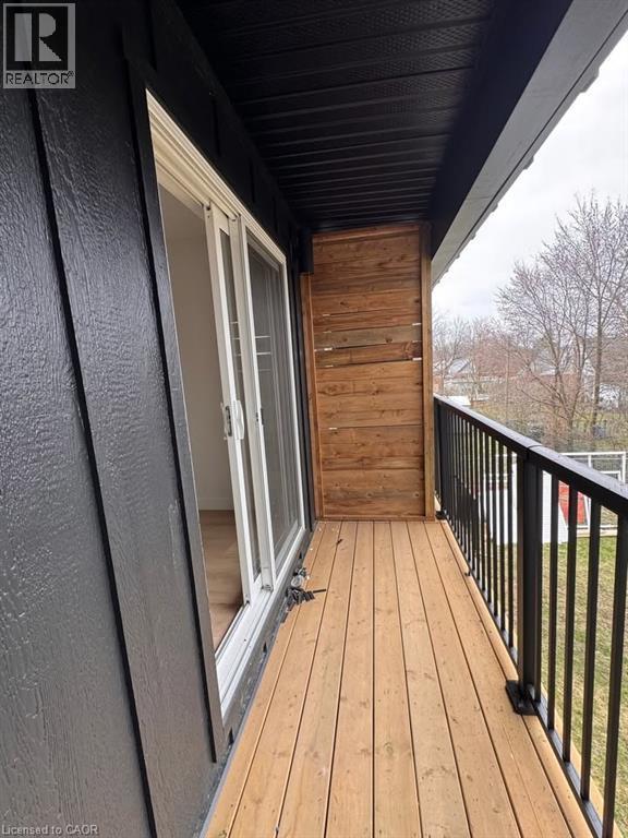 Exterior balcony featuring natural wood decking, black metal railings, and a sliding glass door - 431 Krug Street, Kitchener, ON - Outdoor With Exterior