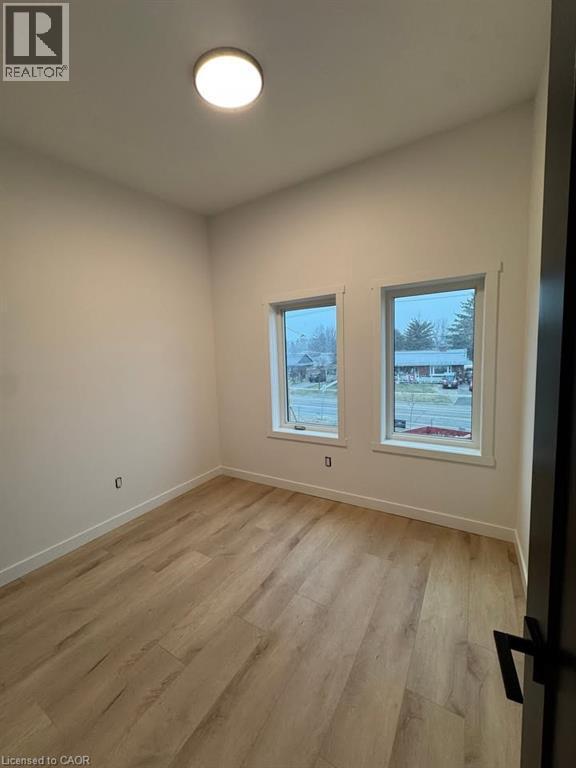 Room featuring wood-finish flooring, white walls, two windows, a ceiling-mounted light fixture, and white baseboards - 431 Krug Street, Kitchener, ON - Indoor Photo Showing Other Room