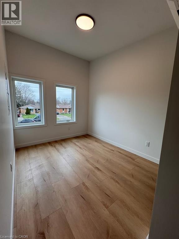 Bright room featuring two windows, wood-finish flooring, white baseboards, and a flush-mount ceiling light - 431 Krug Street, Kitchener, ON - Indoor Photo Showing Other Room