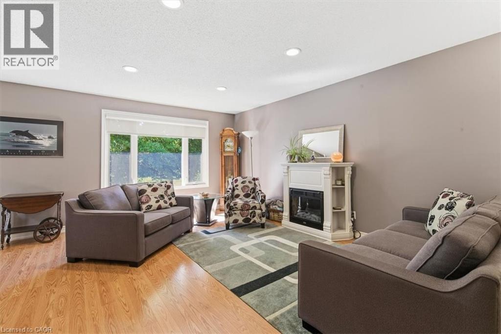 Living area featuring wood-finish flooring, recessed lighting, a large window, and a white decorative fireplace surround with an electric insert - 26 Sideroad 18, Fergus, ON - Indoor Photo Showing Living Room With Fireplace