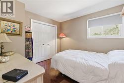 Interior room featuring wood-finish flooring, a double-door closet with white paneled doors, and an exterior window with a roller shade -
