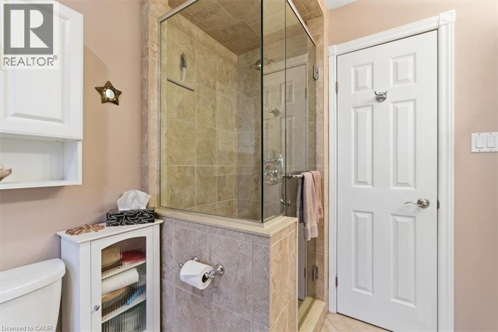Glass-enclosed shower featuring floor-to-ceiling tile surround, a built-in shelf, and a polished chrome shower system - 26 Sideroad 18, Fergus, ON - Indoor Photo Showing Bathroom