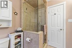 Glass-enclosed shower featuring floor-to-ceiling tile surround, a built-in shelf, and a polished chrome shower system -