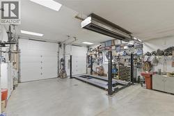 Spacious garage featuring two overhead doors, a four-post vehicle lift, concrete flooring, and built-in shelving -