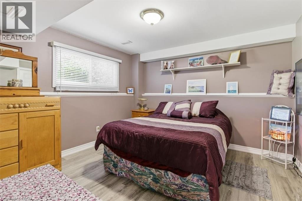 Bedroom featuring wood-finish flooring, a contemporary ceiling light fixture, and a window with white blinds - 26 Sideroad 18, Fergus, ON - Indoor Photo Showing Bedroom