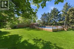 Expansive green lawn featuring a built-in swimming pool with a surrounding wood deck and privacy railing -