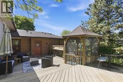 Expansive wood deck featuring a screened gazebo, brick exterior, and multiple access points -