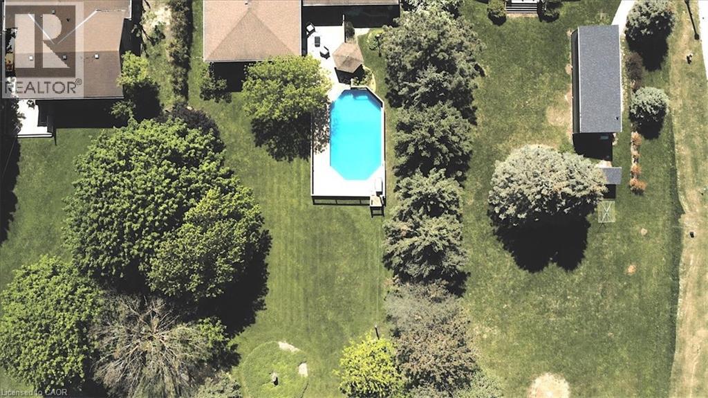 Manicured grounds featuring an inground swimming pool with a surrounding deck, mature trees, and a detached outbuilding - 26 Sideroad 18, Fergus, ON - Outdoor With View
