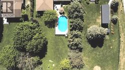 Manicured grounds featuring an inground swimming pool with a surrounding deck, mature trees, and a detached outbuilding -