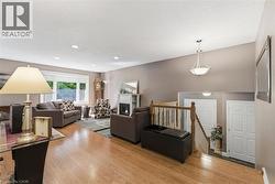 Hardwood-finish flooring extending into a spacious living area featuring a fireplace with a white mantel, recessed lighting, and a chandelier -