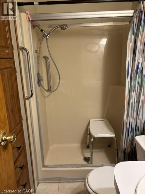 Walk-in shower with a beige surround, chrome shower fixtures, and a sliding glass door - 580 Beaver Creek Road Unit# 203, Waterloo, ON - Indoor Photo Showing Bathroom