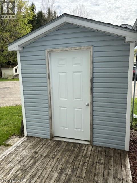Exterior storage shed featuring blue siding, a white paneled door, and a weathered wooden deck - 580 Beaver Creek Road Unit# 203, Waterloo, ON - Outdoor With Exterior