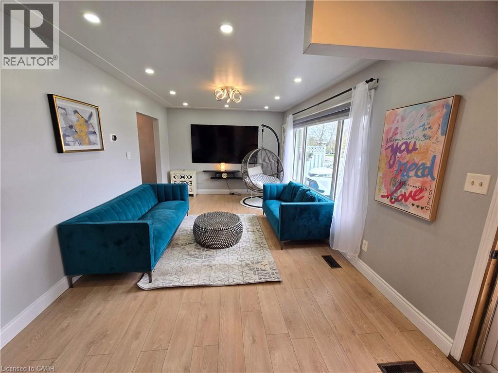 Spacious living area featuring light wood-finish flooring, recessed ceiling lighting, and a modern chandelier - 261 Overlea Drive, Kitchener, ON