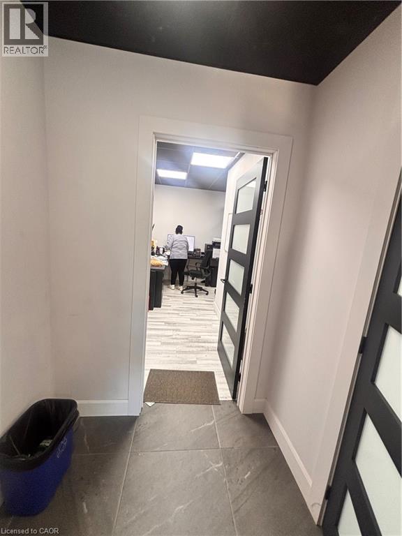 Hallway featuring large format tile flooring, white baseboards, and a contrasting dark ceiling - 277 Lancaster Street W, Kitchener, ON