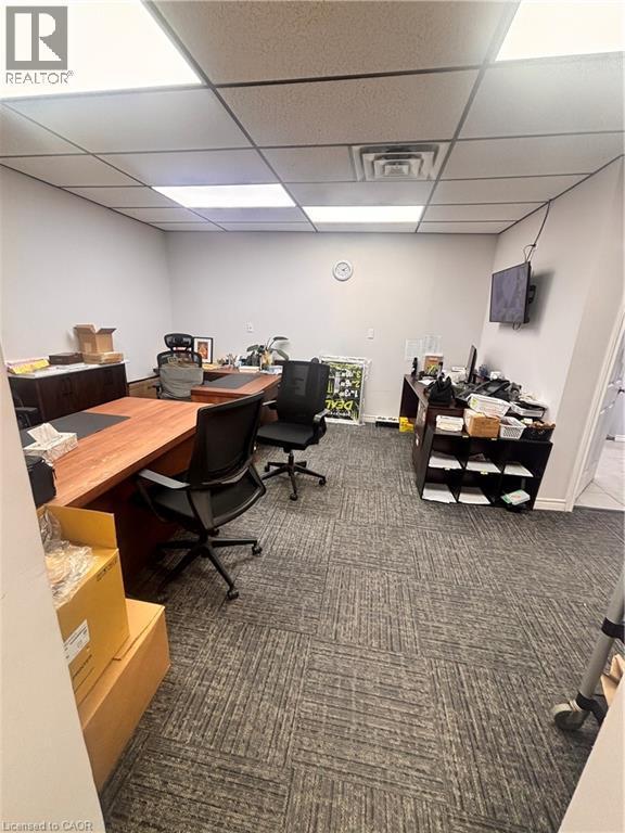 Spacious office interior featuring patterned carpet flooring, neutral painted walls, and a drop ceiling with integrated lighting panels - 277 Lancaster Street W, Kitchener, ON