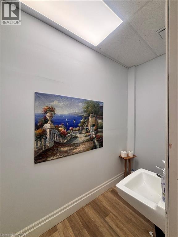Wall-mounted sink with a chrome faucet, set against light gray walls with white baseboards, and wood-finish flooring - 1400 Weber Street E Unit# A5, Kitchener, ON