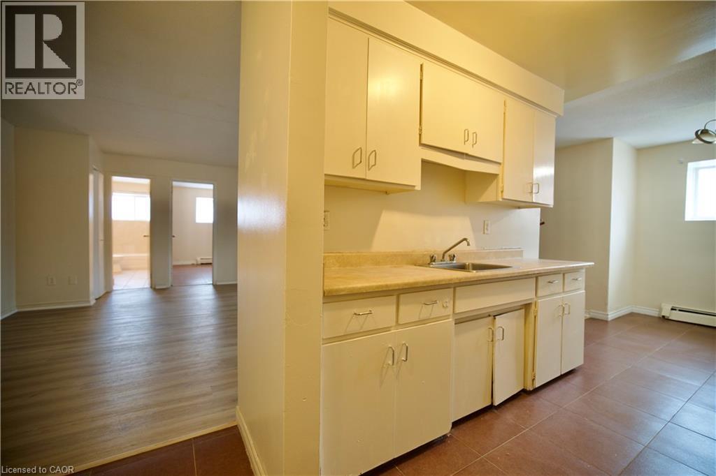 Kitchen featuring white cabinetry, a double basin sink, and laminate countertops - 223 Heiman Street Unit# Unit 2, Kitchener, ON - Indoor Photo Showing Kitchen