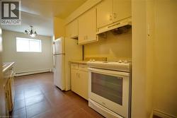 Kitchen featuring white cabinetry, a freestanding electric range, and a refrigerator -