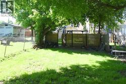 Expansive grassy yard area with mature trees providing shade -