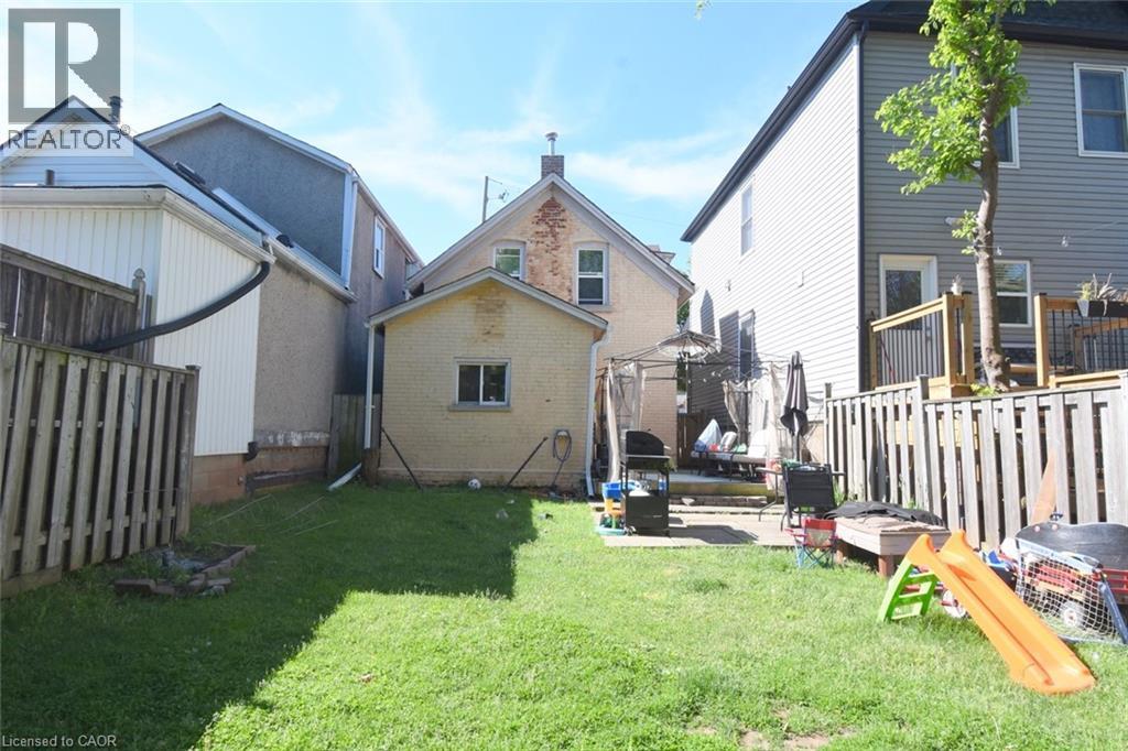 Expansive rear yard featuring a manicured lawn, full privacy fencing, and a paved patio area - 12 Wood Street W, Hamilton, ON - Outdoor