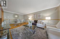 Open-concept living space featuring wood-finish flooring, crown molding, and a neutral color palette -