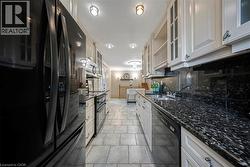 Galley kitchen featuring light-toned cabinetry with glass-front accents, dark speckled countertops, and a coordinating backsplash -