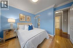 Hardwood flooring and crown molding in a room featuring a mirrored closet -