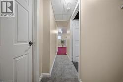 Hallway featuring neutral-toned walls, white trim, and gray textured carpeting -