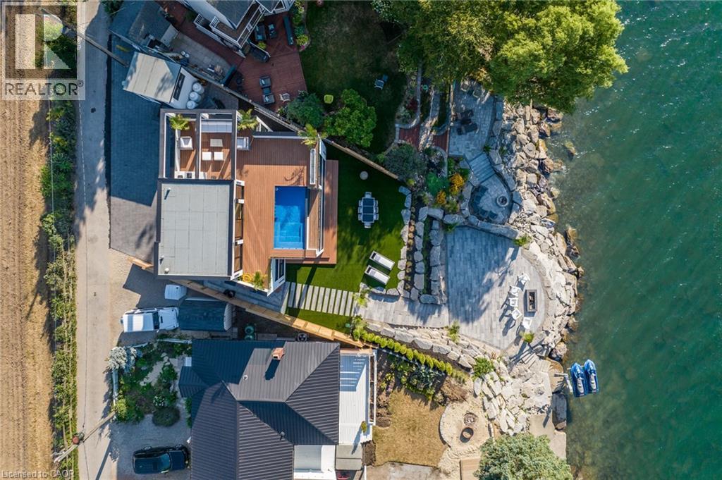 Waterside property featuring a multi-level rock and stone patio, a private dock, an artificial turf lawn, a deck with an integrated swimming pool, and a rooftop terrace - 6 Firelane 11A Street, Niagara-On-The-Lake, ON - Outdoor With Body Of Water