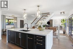 Spacious kitchen island featuring a white countertop, undermount sink, matte black faucet, and dark cabinetry with brass-tone hardware -