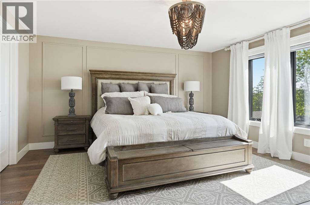 Spacious room featuring wood-finish flooring, a decorative ceiling fixture, and wall paneling - 71 Miles Road, Hamilton, ON