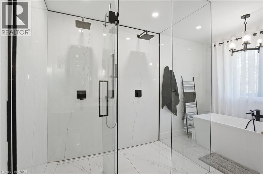 Modern bathroom featuring a spacious glass-enclosed shower with dual rain showerheads and matte black fixtures - 71 Miles Road, Hamilton, ON