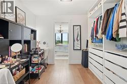 Walk-in closet featuring light wood-finish flooring, white walls, and built-in closet systems with shelving and drawers -
