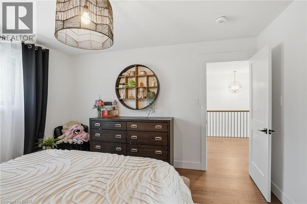 Bedroom featuring light wood-finish flooring and a contemporary woven pendant light fixture - 71 Miles Road, Hamilton, ON