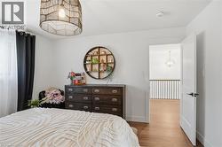 Bedroom featuring light wood-finish flooring and a contemporary woven pendant light fixture -