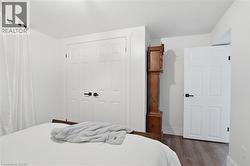 Interior space featuring wood-finish flooring, white paneled doors with black hardware, and ample natural light from a window with sheer white curtains -