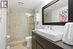 Modern bathroom featuring a frameless glass shower enclosure, beige tile shower surround, and a rectangular vessel sink -