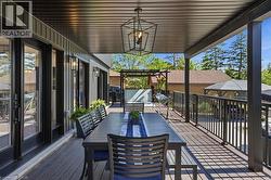 Expansive covered deck featuring composite decking, black metal railings, and a contemporary geometric pendant light -