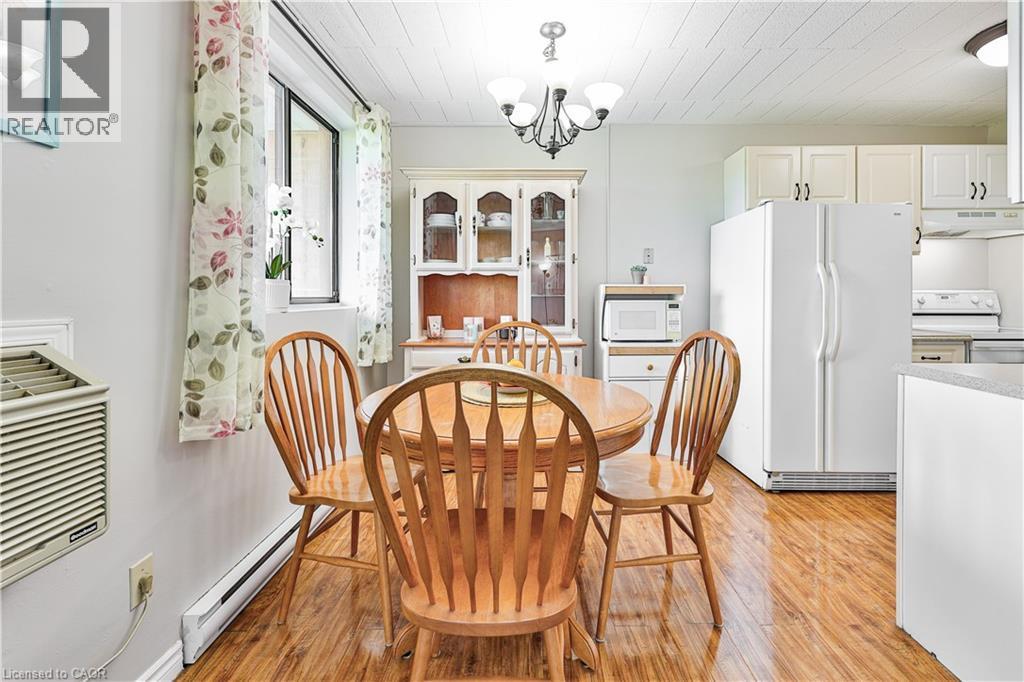 Dining area featuring wood-finish flooring, a decorative chandelier, and a window with natural light - 29 West Avenue, Kitchener, ON