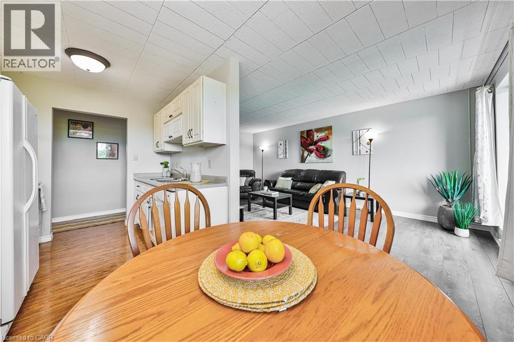 Open-concept dining area with wood-finish flooring, a round wooden table, and slat-back chairs - 29 West Avenue, Kitchener, ON