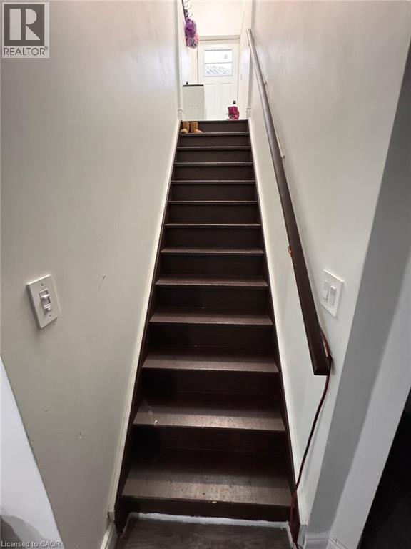 Staircase with dark-stained wood treads and a matching handrail, framed by light-colored walls - 1377 Coronation Drive, London, ON - Indoor Photo Showing Other Room