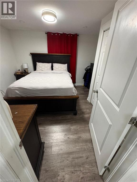 Neutral wall paint and wood-finish flooring with a modern flush-mount ceiling light - 1377 Coronation Drive, London, ON - Indoor Photo Showing Bedroom