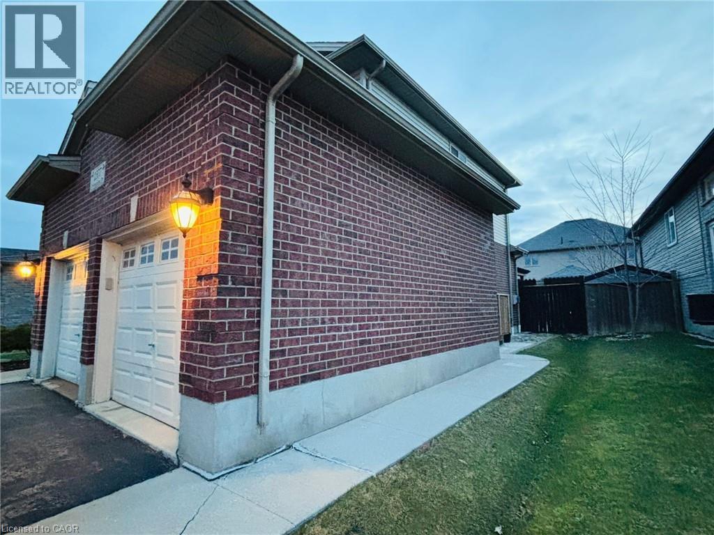 Brick exterior featuring two garage doors with window accents and traditional wall-mounted lanterns - 1377 Coronation Drive, London, ON - Outdoor