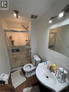 Contemporary bathroom featuring a shower with a sliding glass door, a wall-mounted sink, and track lighting -